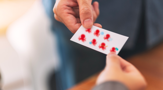 deux humains qui se partagent une carte de visite contenant des poulpes rouges
