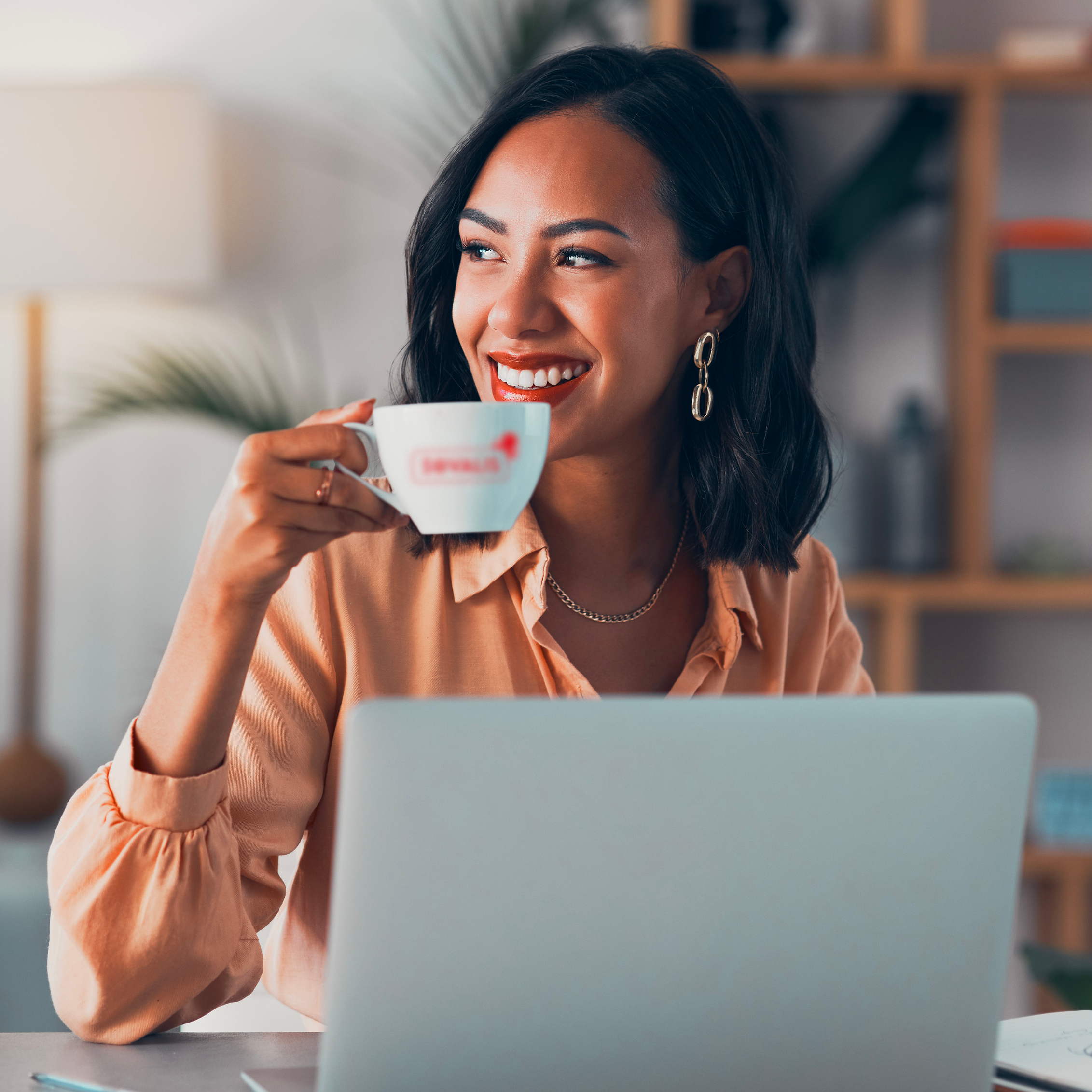 Femme qui boit son café devant son ordinateur